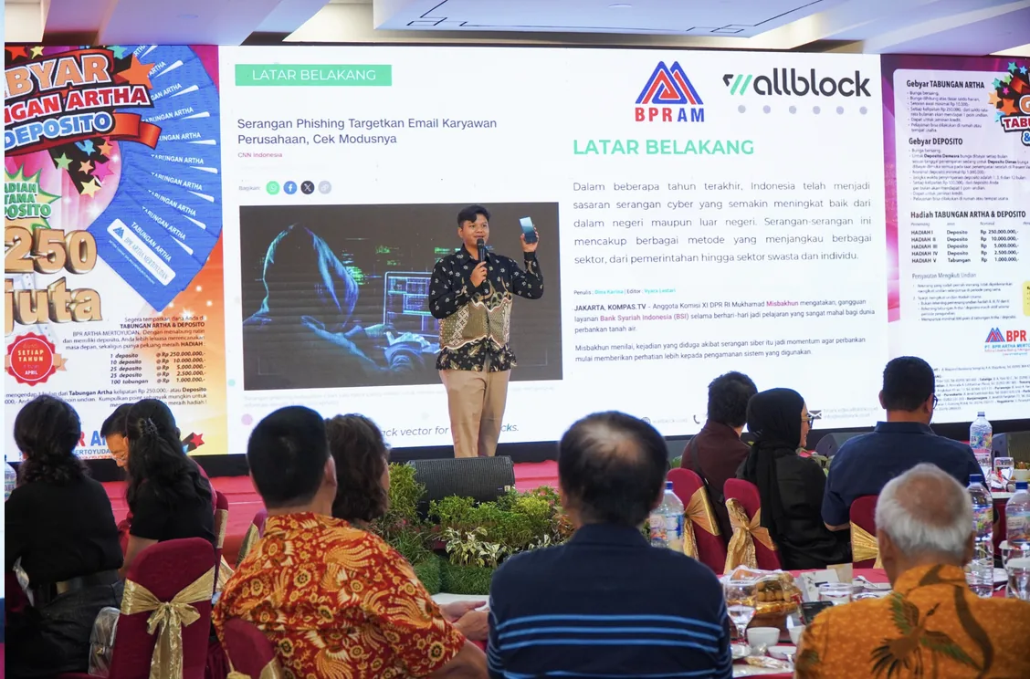 Pembicara Wallblock membawakan materi keamanan siber di depan tamu undangan Customer Gathering BPR Artha Mertoyudan, dengan slide berjudul Latar Belakang di layar.